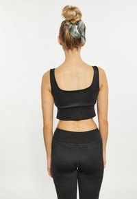 Top scurt negru cu bretele late, asortat cu colanți negri cu talie înaltă. Material neted cu un design ajustat, cu cusături minime vizibile.