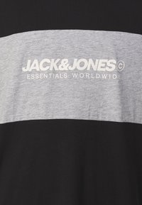 Zwarte en grijze korte mouwen t-shirt met een horizontale streep, het heeft een witte opdruk met de tekst "JACK & JONES ESSENTIALS WORLDWIDE." Zachte stofstructuur.