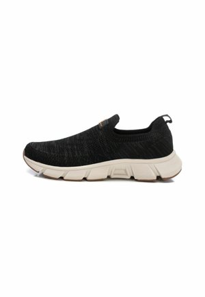 Zapato negro tipo slip-on con parte superior de tejido, patrón texturizado y una suela de goma blanca acolchada. Cuenta con una lengüeta para facilitar el calzado.