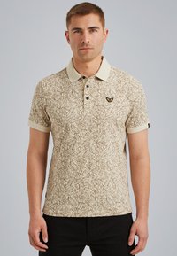 Polo beige con un motivo astratto marrone, maniche corte, colletto a contrasto e un piccolo logo ricamato sul petto.