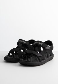 Svarta sandaler med flera justerbara remmar, öppen tå-design, texturerad fotbädd och logotyp på remmen. Lätt gummisula med bra grepp.