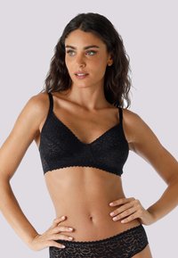 Bralette in pizzo nero a forma triangolare, con spalline sottili regolabili, bordi smerlati e motivi floreali. Abbinato a culotte in pizzo coordinate.