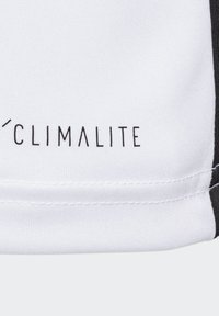 Tela blanca con el logotipo "CLIMALITE" impreso en negro, con costuras visibles y una textura suave, acentuada por una franja lateral oscura.