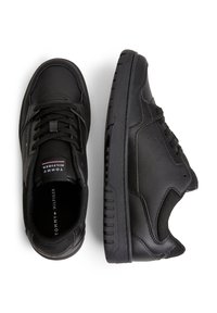 Mustat tennarit, joissa on sileä nahkapinta, verkkoyksityiskohtia ja kumipohja. Ominaisuuksia ovat yksinkertainen nauhoitus, pehmustettu varsi ja merkitty sisäpohja.