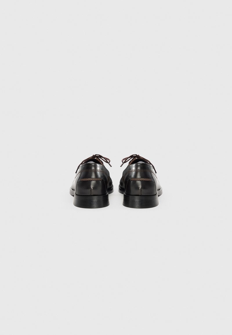 Chaussures habillées en cuir noir avec une finition lisse, bout arrondi et lacets. Présentent un talon bas et des détails de couture subtils.