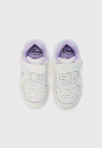 Baskets blanches pour enfants avec doublure violette, logo Disney Stitch sur la sangle, et zone de orteils perforée, montrées de dessus sur un fond blanc.