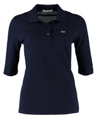 Polo Lacoste bleu marine à manches trois-quarts, col boutonné et petit logo crocodile sur la poitrine gauche.