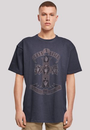 Navy blue cotton t-shirt featuring a printed graphic of a cross with skulls and the text "GUNS N' ROSES" and "APPETITE FOR DESTRUCTION."