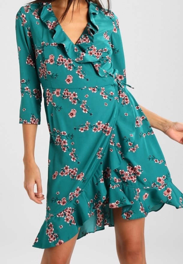 Türaus Kleid in Petrol mit dreiviertel Ärmeln, rüschigem Ausschnitt und floralem Muster in Rosa und Weiß. Mit ausgestelltem Saum und weichem Stoff.