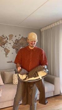 Borsa marrone tenuta da una persona, caratterizzata da una texture morbida e da più scomparti. La persona indossa una maglia a maniche corte in maglia di colore ruggine.