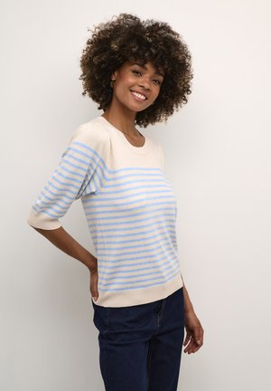 Pull rayé beige clair avec des rayures bleues, col rond et manches trois-quarts, associé à un jean bleu foncé. Texture lisse.
