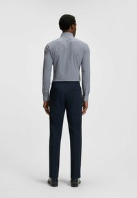 Sininen ja valkoinen ruutukuosi pitkähihaisessa paidassa, joka on yhdistetty tummansinisisiin housuihin. Paidassa on pystykaulus ja se on muotoiltu istuvaksi.