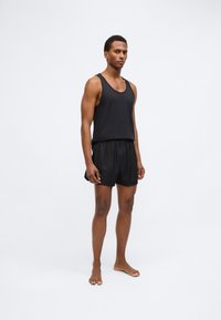 Mustmust särg ja kerged lühikesed püksid. Särgil on ümar kaelus; lühikesed püksid on lõdvalt istuvad ja neil on elastne vöökoht.