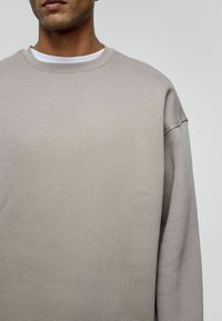 Lichtbeige sweatshirt met een ronde hals, gemaakt van een zachte katoenmix, met zakkende schouders en ingezette mouwen.