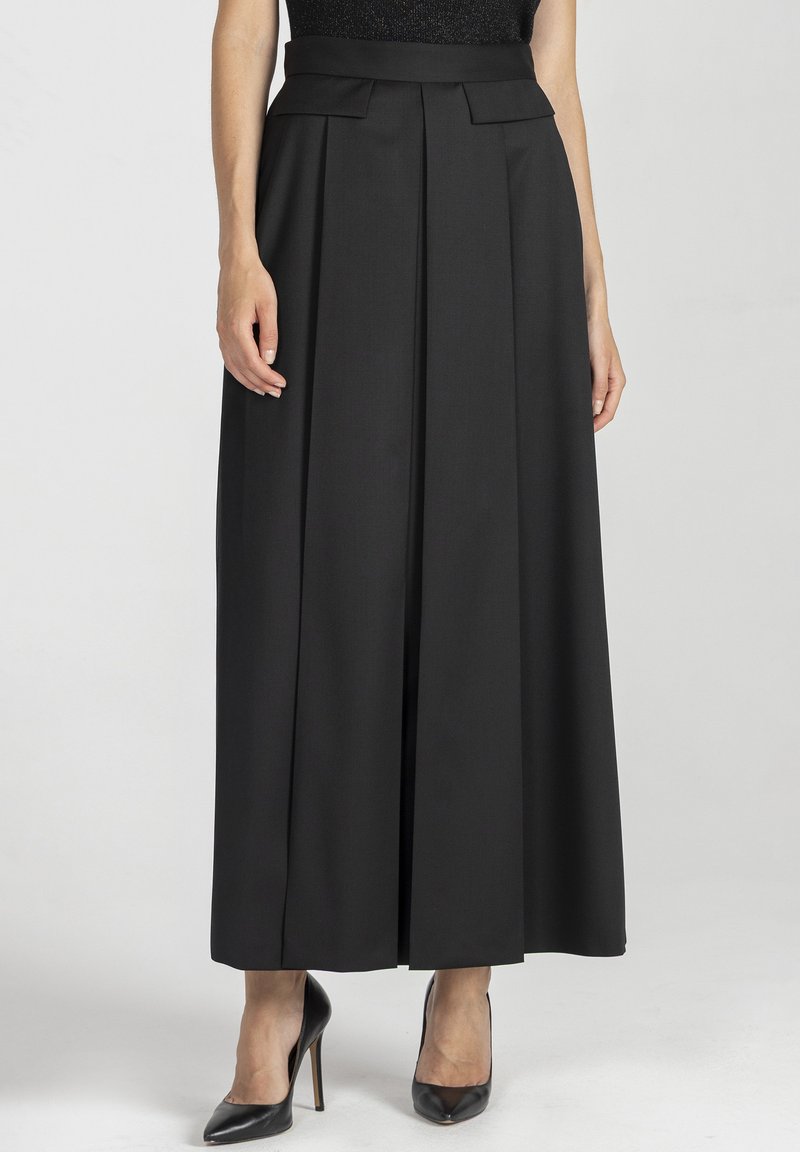 Czarna, plisowana długa spódnica wykonana z fakturowanej tkaniny. Wysoki stan, z bocznymi kieszeniami, noszona z czarnymi szpilkami.