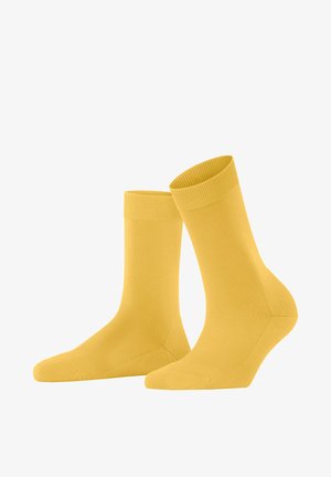 Ein Paar schlichte gelbe Socken bis zur Mitte der Wade mit gerippten Bündchen, aufrecht auf einem weißen Hintergrund dargestellt.