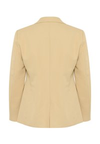 Blazer beige su misura con silhouette strutturata, rever a punta e texture in tessuto morbido. Presenta una fessura centrale sul retro.
