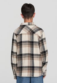 Koszula w kratę z flaneli w beżowych, czarnych i szarych odcieniach, charakteryzująca się luźnym krojem, długimi rękawami i klasycznym kołnierzykiem.