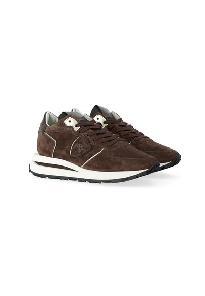 Un paio di sneakers in suede marrone con suole intermedie bianche e suole esterne nere, caratterizzate da allacciatura frontale e colli imbottiti.