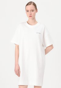 Bijela oversized T-shirt haljina od pamuka, s okruglim izrezom, kratkim rukavima i malim otisnutim logotipom na lijevoj strani prsnog koša.