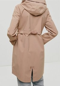 Světle růžový nepromokavý kabát s kapucí, stahovací pas a zadní větračka pro snadný pohyb. Má hladkou texturu a minimalistický design.