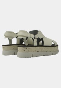 Sandale platform ușor gri, cu curele încrucișate, material texturat și talpă bej cu stropi. Dispune de închideri ajustabile pentru o potrivire perfectă.