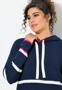 Granatowa bluza z kapturem w białe i różowe paski. Posiada przednią kieszeń typu kangur, kaptur ze sznurkiem i ściągacze przy rękawach. Teksturowany materiał dzianinowy.