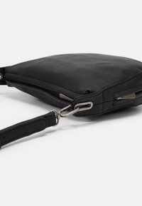 Černá kožená kabelka přes rameno s zipovým uzávěrem, plochým tvarem a kovovými detaily. Texturovaný povrch a nastavitelný popruh.