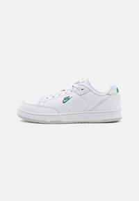Fehér bőr sportcipők sima textúrával, zöld Nike logóval, szürke talppal és minimalista dizájn elemekkel.