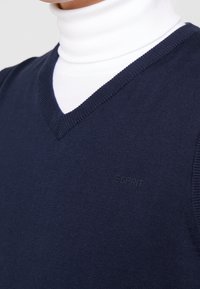 Marineblauer, gestrickter Pullover mit V-Ausschnitt und geripptem Abschluss. Verfügt über ein dezentes "Esprit"-Logo in passender Farbe auf der Brust.