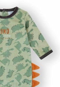 Peto verde para bebé con mangas largas, ribete oscuro, estampado de dinosaurios, picos de tela naranja en el lateral y texto parcial impreso en el frente.