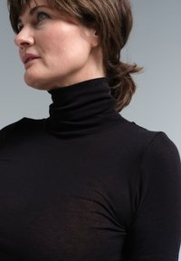 Schwarzes Rollkragenoberteil, enganliegendes Design, weicher Stoff, mit langen Ärmeln und hohem Kragen, leichte Transparenz im Gewebe sichtbar.