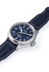 Nerūsējošā tērauda pulksteņi ar apaļu tumši zilu ciferi, baltām ciparnīcām un sudraba stundu/minūšu rādītājiem. Ierīce ir aprīkota ar tumši zilu ādas siksniņu ar vieglu šuvju dekori.