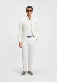 White linen suit with a light blue belt, paired with a white shirt and gray slip-on shoes. Includes sunglasses. Smooth texture, tailored fit.
