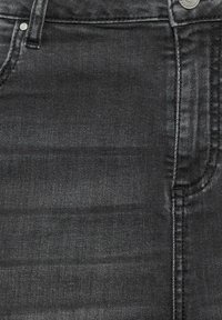 Tejido de mezclilla negro con textura suave, que presenta un brillo sutil, diseño de cinco bolsillos y detalle de botón metálico plateado en la cintura.