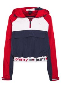 Röd och marinblå vindjacka med vita detaljer, halvdragkedja framtill, stor ficka fram och elastisk nederkant med "tommy jeans"-logotyp.