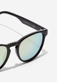 Ochelari de soare negri cu un finisaj lucios, în formă de ochi de pisică, și lentile reflectorizante care prezintă un gradient de la verde deschis la albastru.