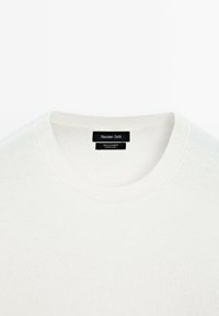 Weißer Kaschmirpullover mit rundem Ausschnitt, ausgestattet mit einem gerippten Kragen und einem klaren Design. Das Etikett trägt die Aufschrift "Massimo Dutti, 100 % Kaschmir."