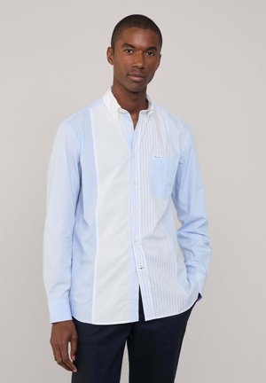 Hellblau gestreiftes Button-Up-Hemd mit einem weißen Einsatz, Kragen und Brusttasche. Verfügt über kontrastierende dünne und breite Streifen.
