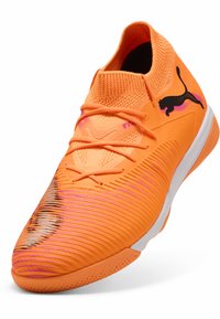 Puma orange idrætssko med tekstureret overdel, sømløst design og sort logo. Har rosa og sølv detaljer på tåområdet.
