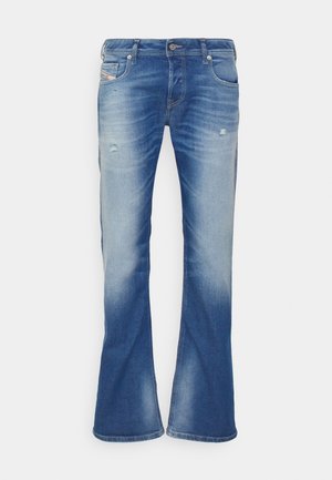 Vaqueros bootcut desgastados en azul con ligero desgarro en los muslos delanteros y diseño clásico de cinco bolsillos sobre fondo blanco.