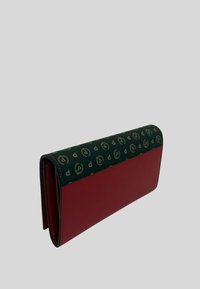 Portafoglio di pelle rossa con una patta decorata da un motivo verde. La patta presenta un design di logo ripetuto, e la texture è liscia con cuciture visibili.