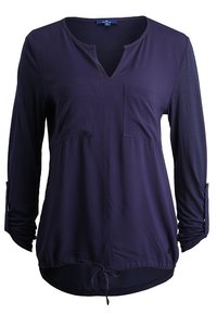 Blusa de manga larga azul marino con escote en V, dos bolsillos en el pecho, mangas enrolladas y un cordón ajustable en la cintura. Textura de tejido suave.
