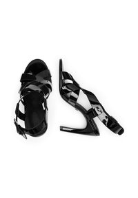 Melnas lakotas ādas augstpapēžu sandales ar krustveida siksnām un atvērtu papēdi. Iespējas ietver smailu purngalu un stilantu papēdi.