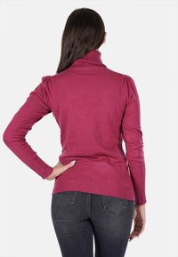 Maglione aderente a collo alto in tessuto rosa con orlo e maniche a coste. Presenta dettagli sulle spalle e una texture liscia.