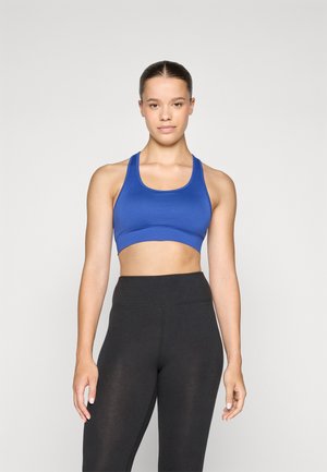 Blå sportbh med en tettsittende design og brede stropper, kombinert med høyspent svarte tights med et glatt, strukturert stoff.