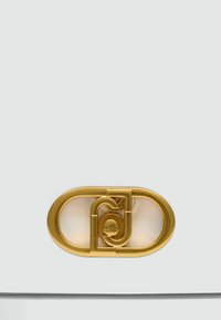 Valge nahast kott kuldse ovaalse klambriga, millel on omavahel seotud disainielemendid ja ringikujulised aktsendid. Siledat tekstuuri, minimalistlik stiil.