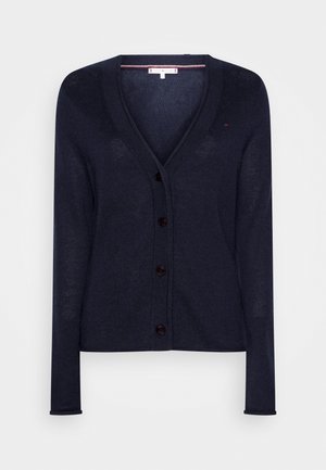 Cardigan marine, tricot léger, col en V, sept boutons sur le devant, manches longues, poignets et ourlet côtelés, design minimal, texture douce.