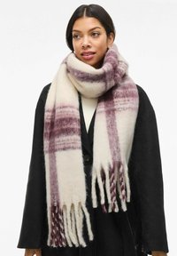 Bufanda de lana con base color crema y un patrón de cuadros en burdeos oscuro, rematada con bordes con flecos. Se lleva colocada alrededor del cuello.