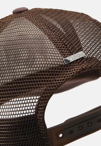 Brown mesh cap featuring a rounded top, a felt button, and a metallic logo accent on the side. Includes an adjustable snapback closure.